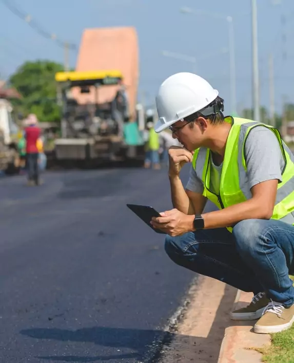 Man in hardhat studying pavement.