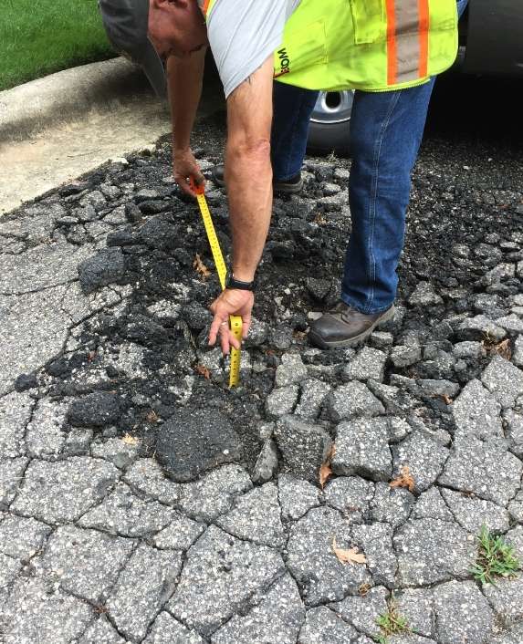 Man measuring a cracked piece of pavement.